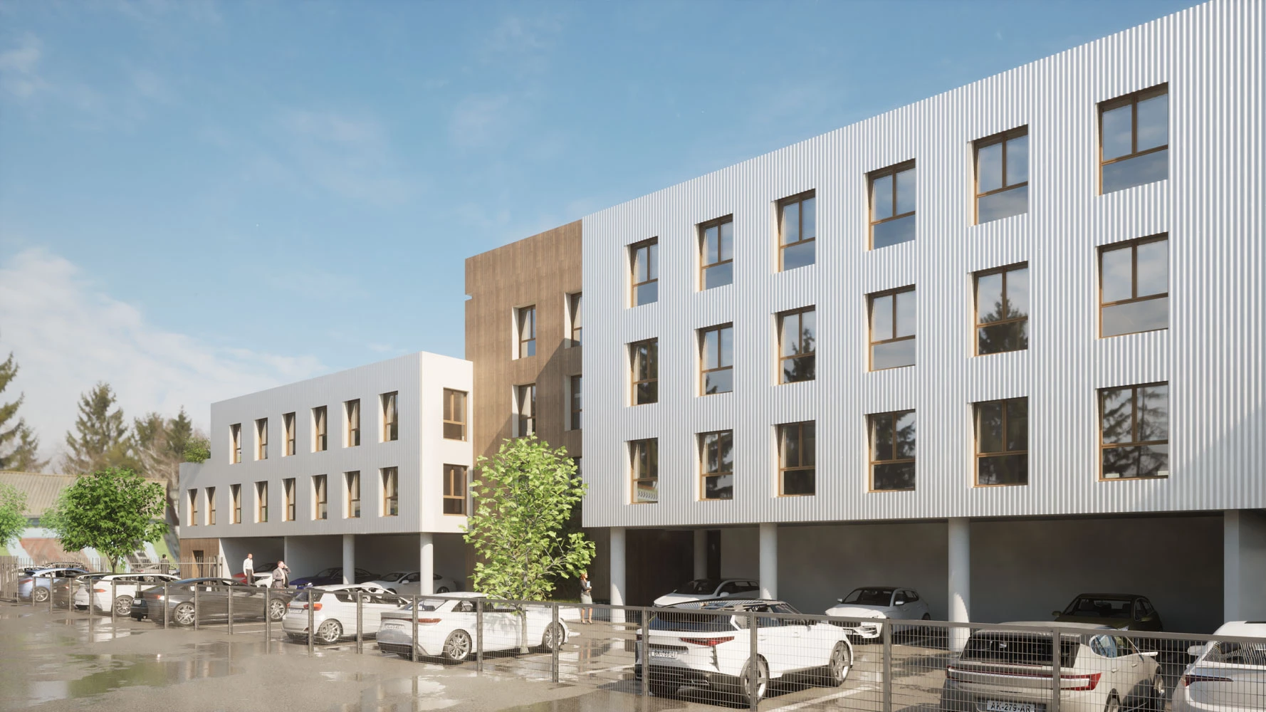 Façade de l'immeuble de bureau sur pilotis avec le parking, on voit sur le bâtiment de la peinture blanche avec un bardage en bois clair.